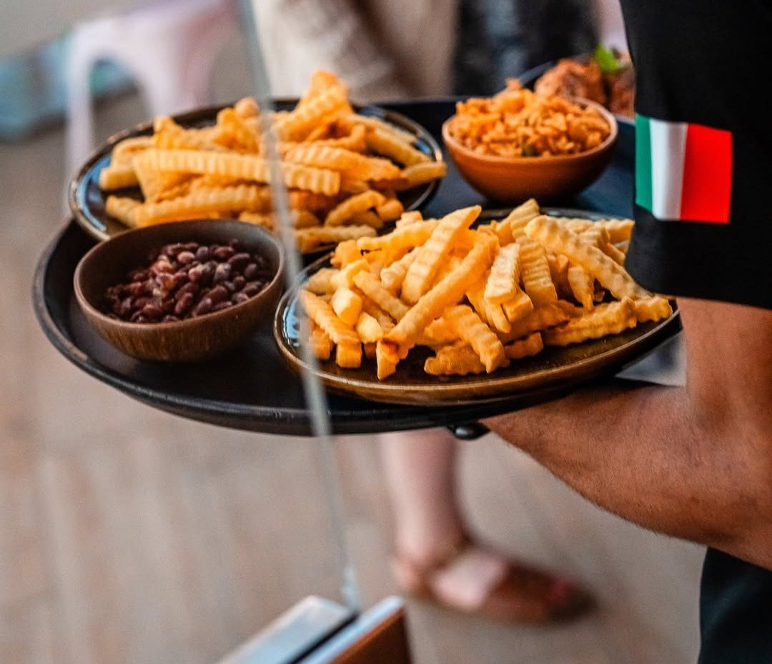 Tabuleiro com dois pratos de batatas fritas onduladas, uma taça de feijão e outra de arroz