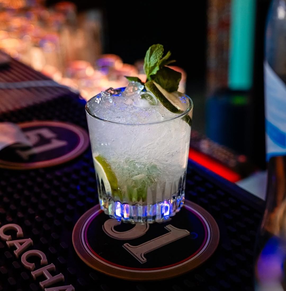 Caipirinha com gelo picado, lima e hortelã num copo baixo sobre o balcão